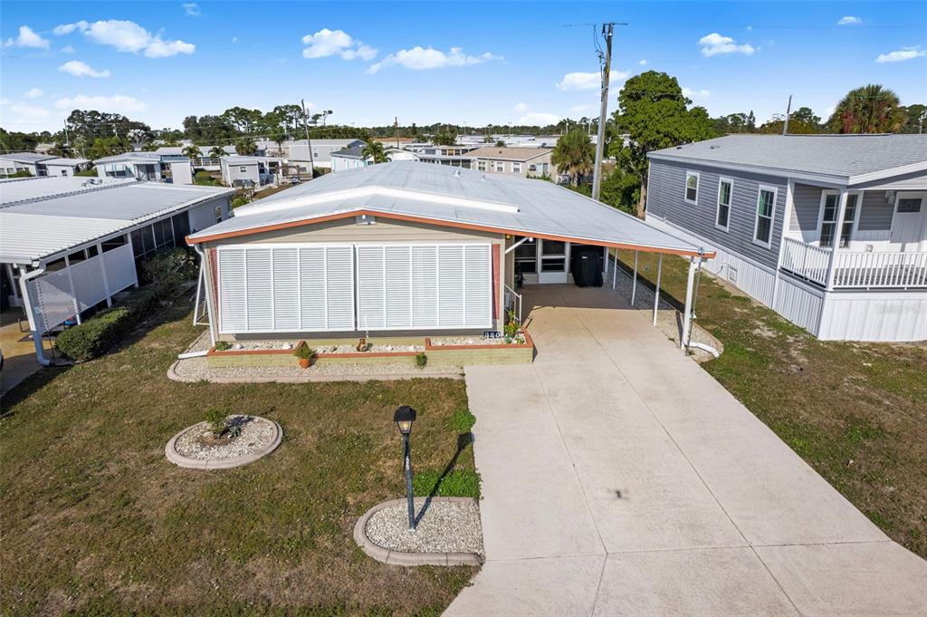 A single-story manufactured home with a concrete driveway, carport, and white shutters — 320 LA COSTA, NORTH PORT, FL