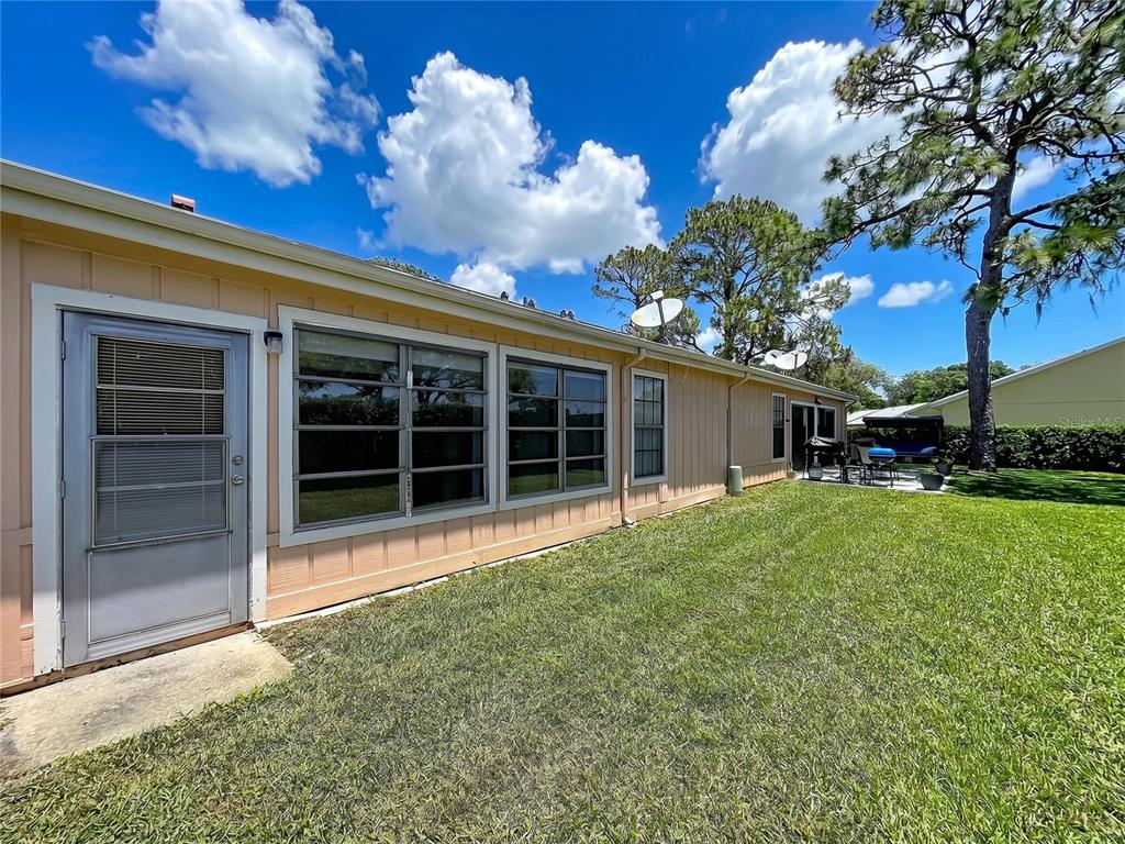 The exterior of a peach-colored house features a back door, windows, and a grassy yard — 9319 TROWBRIDGE COURT, NEW PORT RICHEY, FL
