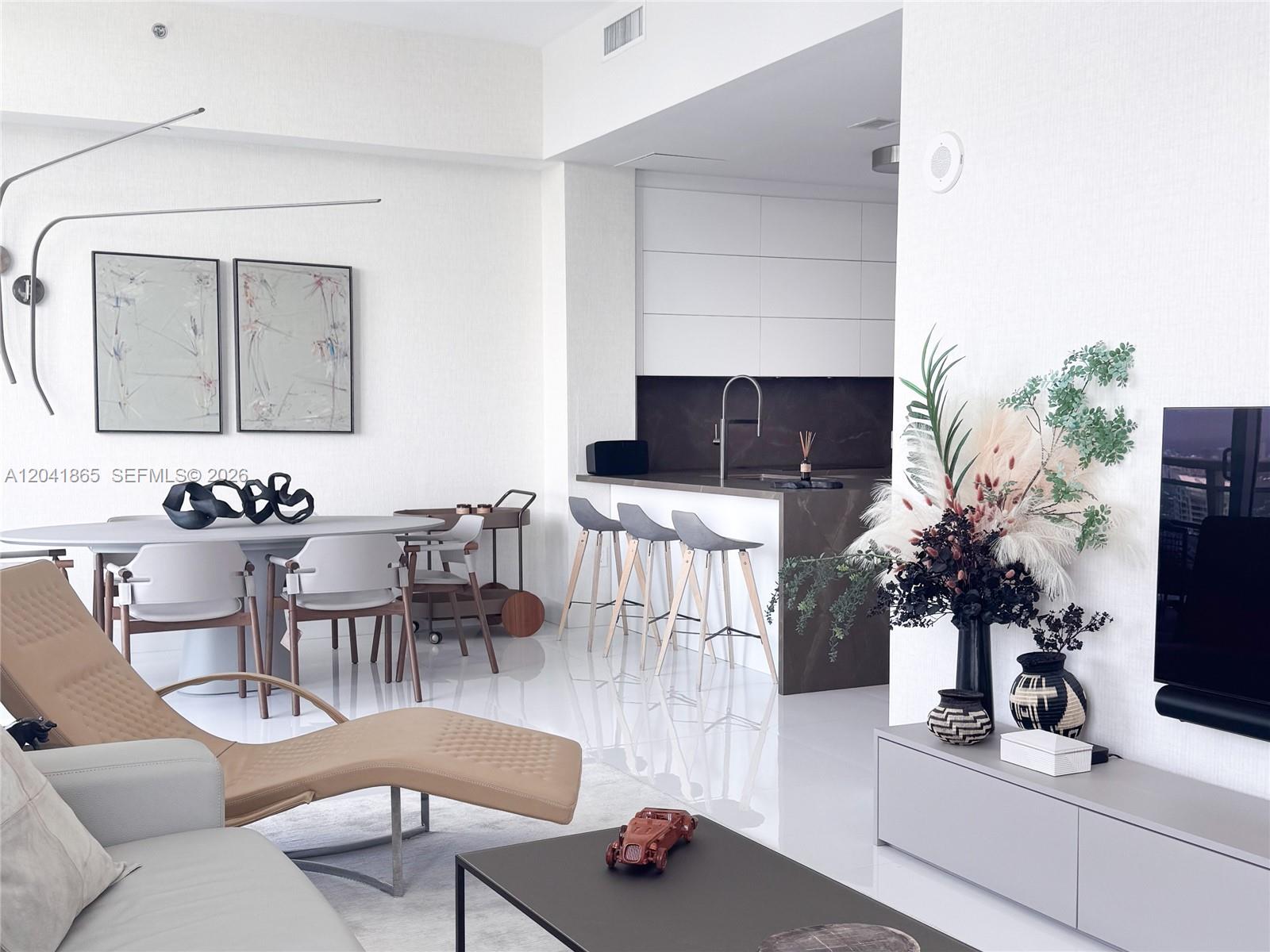 A modern living and dining area features white tile floors, a kitchen island, and contemporary furniture — 950 Brickell Bay Dr # 5608, Miami FL 33131, MIAMI, FL
