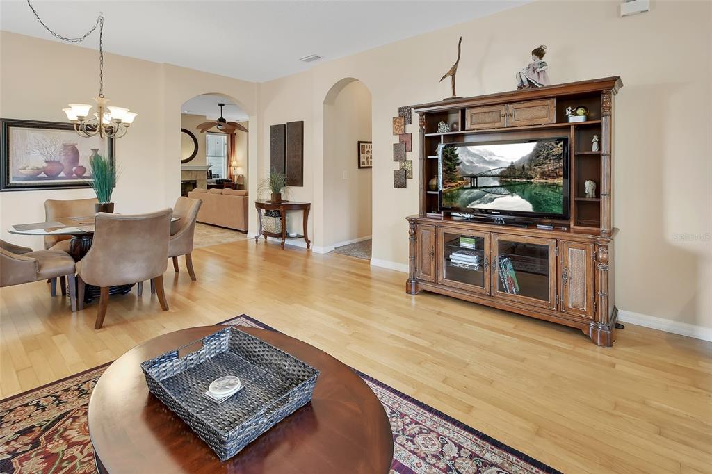 A living room and dining area feature hardwood floors, an entertainment center, and arched doorways — 411 GARDEN STREET, LAKE HELEN, FL