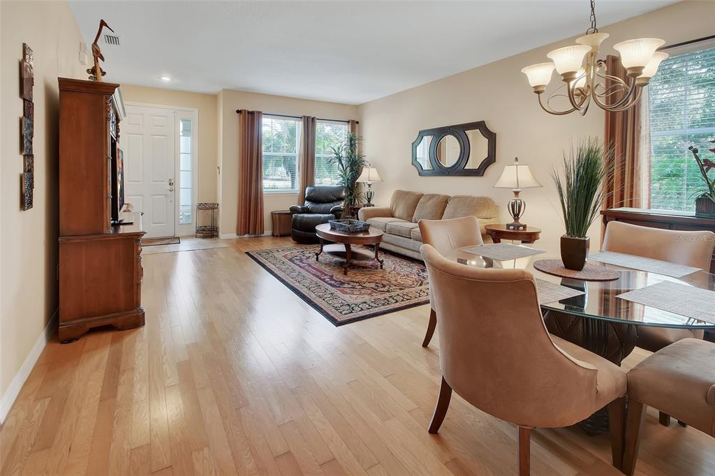 A living and dining area with hardwood floors, a beige sofa, and a glass-topped table — 411 GARDEN STREET, LAKE HELEN, FL