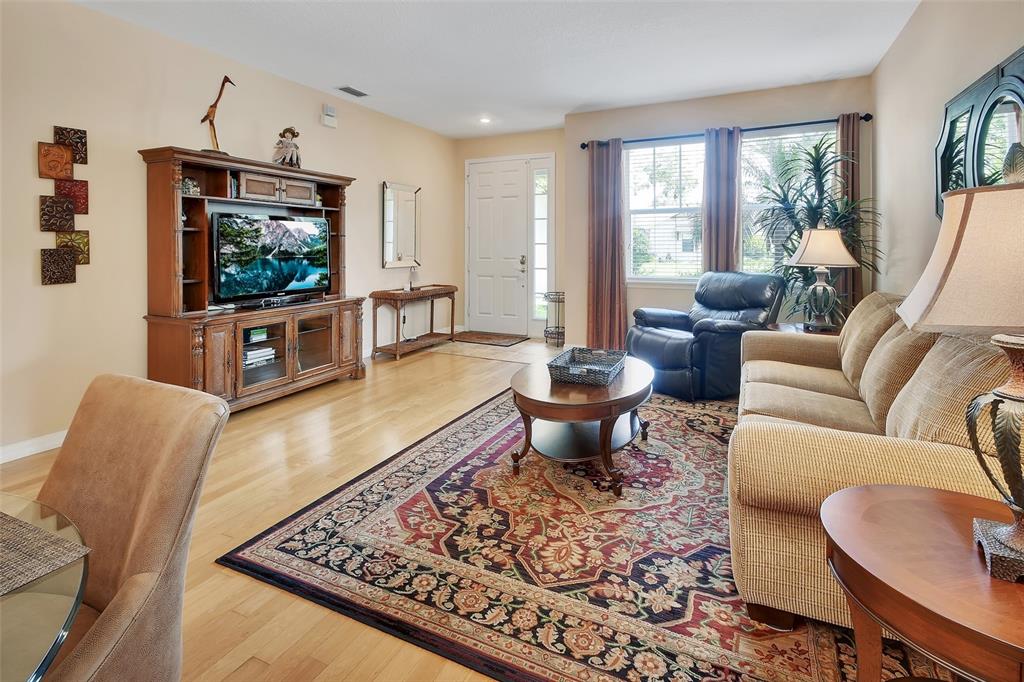 A living room features hardwood floors, a large area rug, a sofa, and an entertainment center — 411 GARDEN STREET, LAKE HELEN, FL