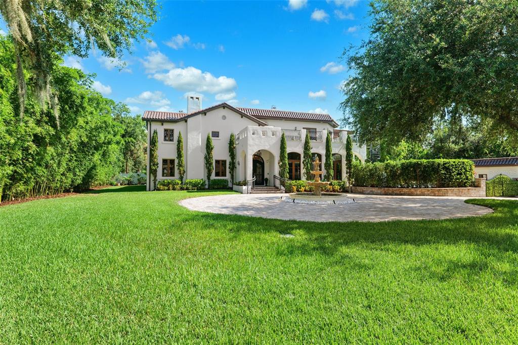 A two-story white stucco house features a circular stone driveway and a central fountain — 4555 W SWANN AVENUE, TAMPA, FL