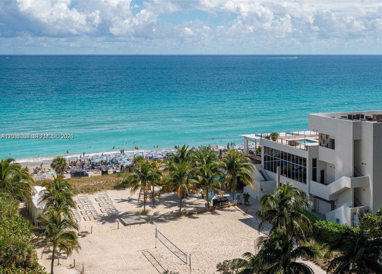 An aerial view shows a beach with palm trees, a volleyball court, and a modern building — 4001 S Ocean Dr # 11A, Hollywood FL 33019, HOLLYWOOD, FL