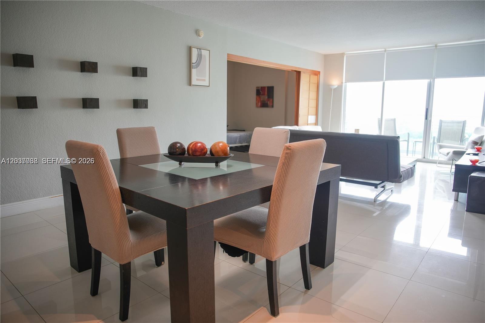 A dining area features a dark wood table with four chairs on a tiled floor — 4001 S Ocean Dr # 11A, Hollywood FL 33019, HOLLYWOOD, FL