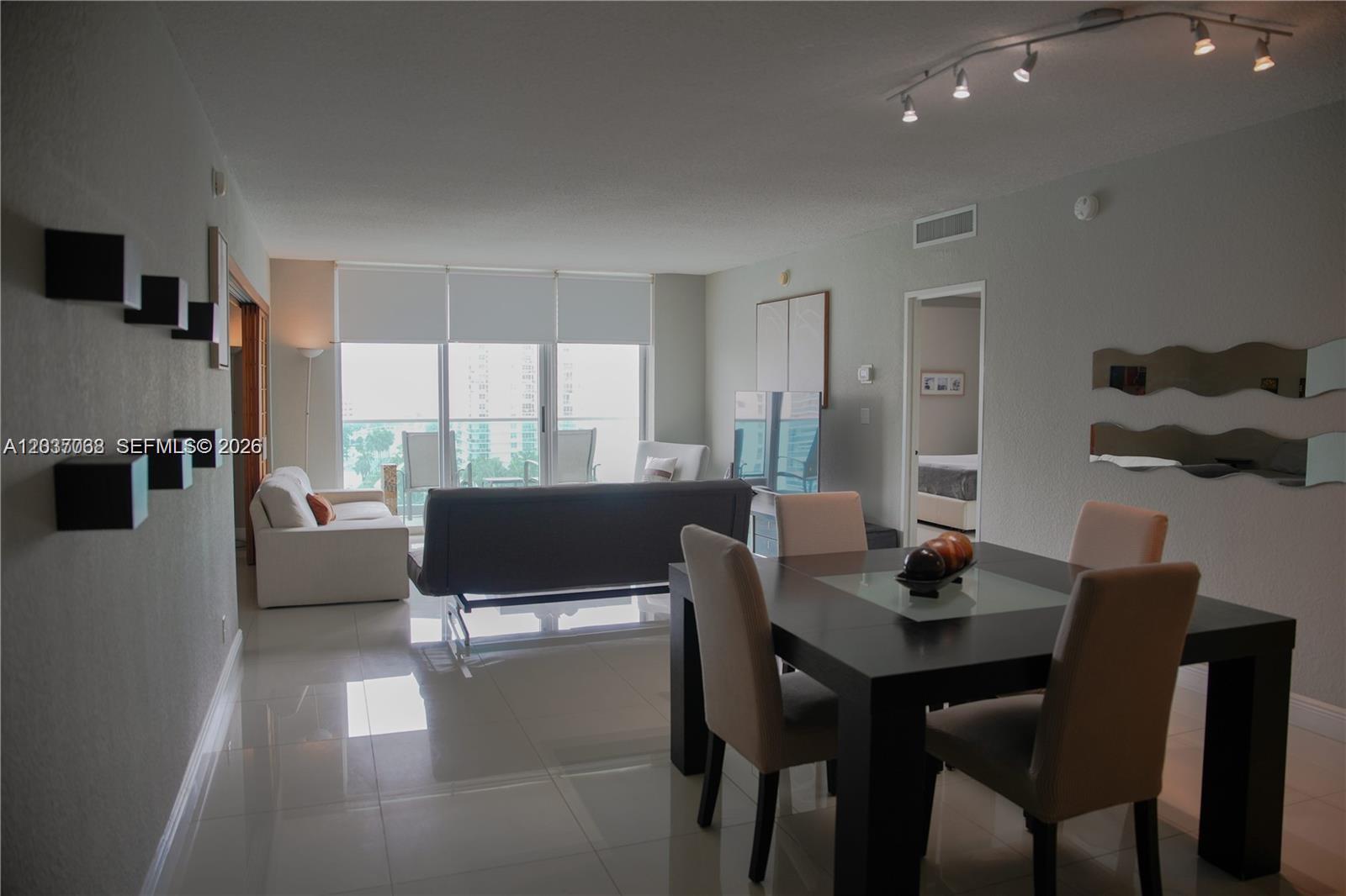 A living and dining area features tile floors, a dark dining set, and balcony access — 4001 S Ocean Dr # 11A, Hollywood FL 33019, HOLLYWOOD, FL