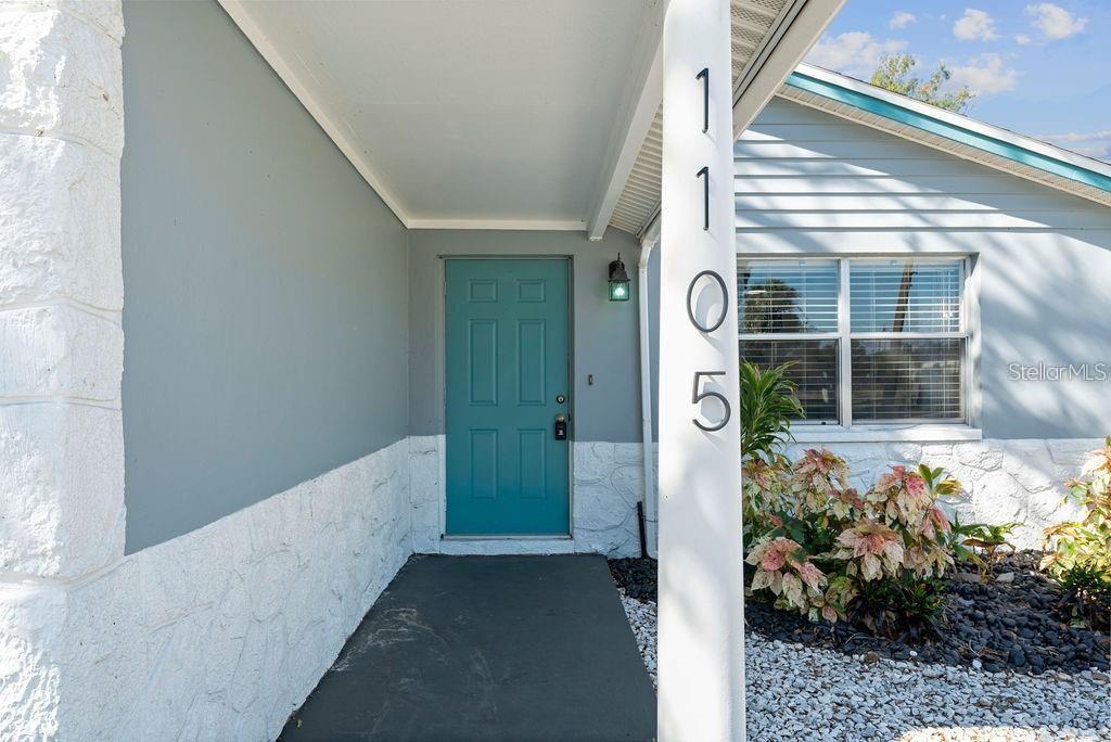 A teal front door is centered on a covered porch with a white support column — 1105 58TH STREET S, ST PETERSBURG, FL