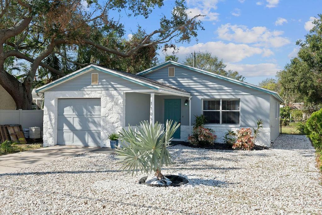 A single-story house with a white stone facade, gray siding, and a gravel front yard — 1105 58TH STREET S, ST PETERSBURG, FL