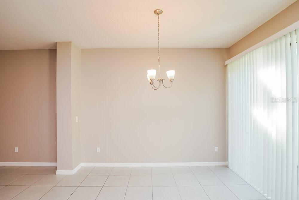 A dining area features light-colored tile flooring, a chandelier, and vertical blinds on the window — 1310 E 10TH STREET, APOPKA, FL