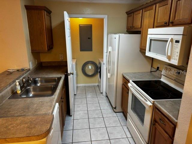 A kitchen features wood cabinets, a double sink, a white refrigerator, and a laundry area — 4850 51ST STREET W UNIT 4207, BRADENTON, FL