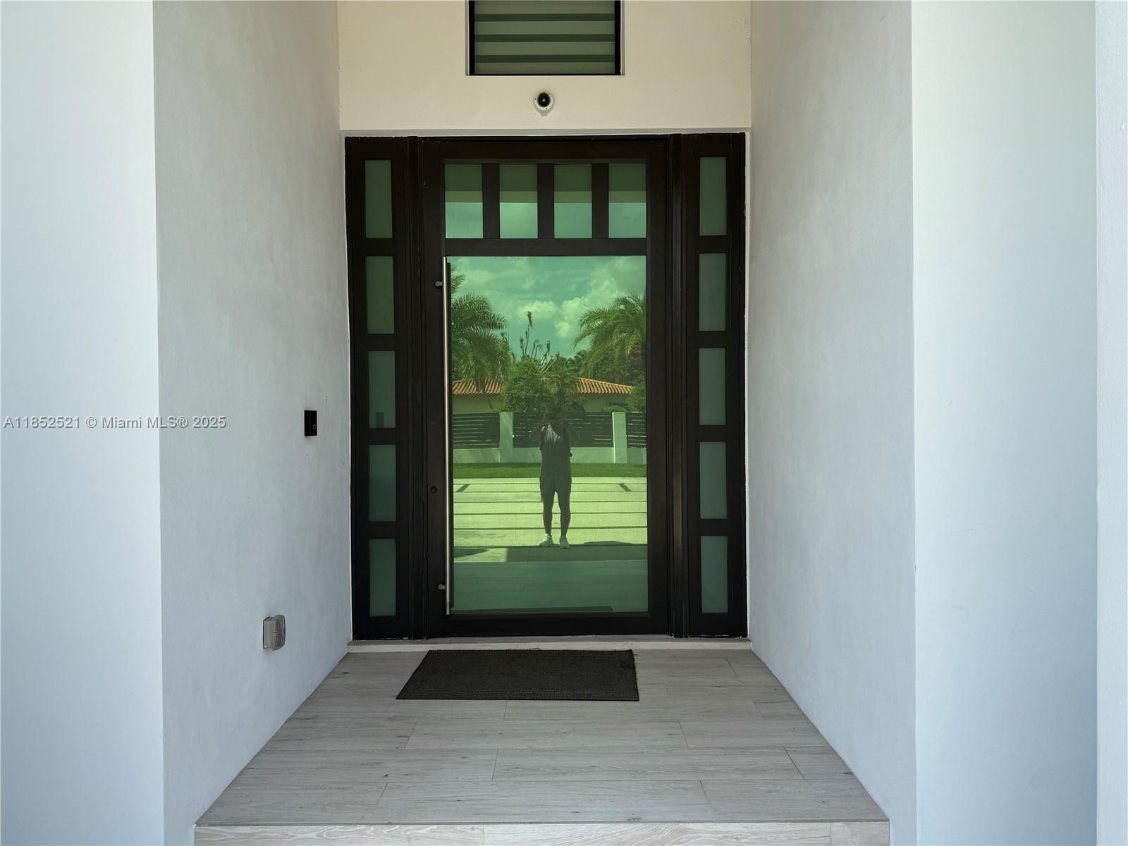 A modern front entrance features a dark-framed glass door with sidelights and tiled flooring — 9600 SW 66th St, Miami FL 33173, MIAMI, FL