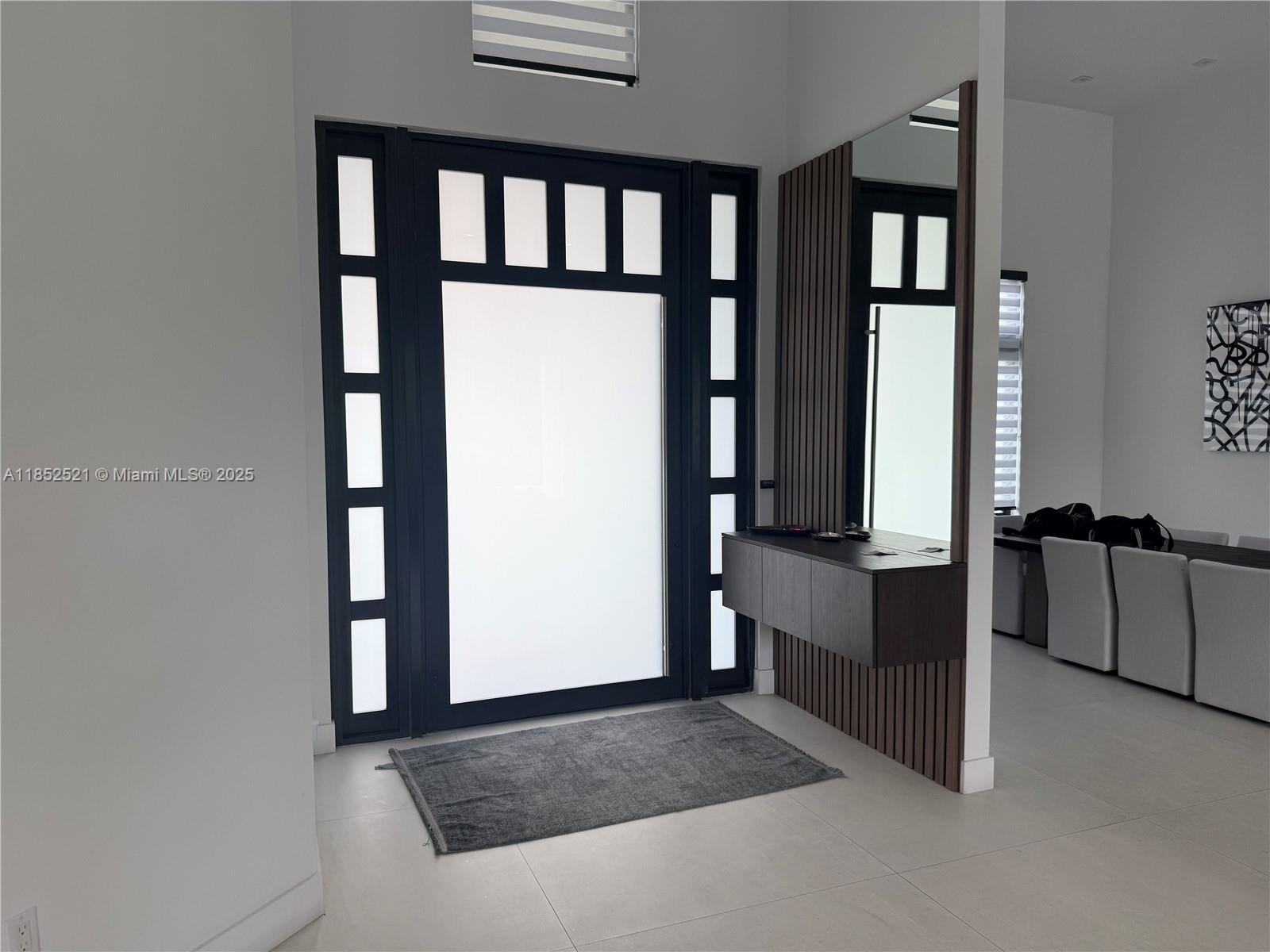 An entryway features a dark-framed glass door, a floating console table, and wood-slat wall paneling — 9600 SW 66th St, Miami FL 33173, MIAMI, FL