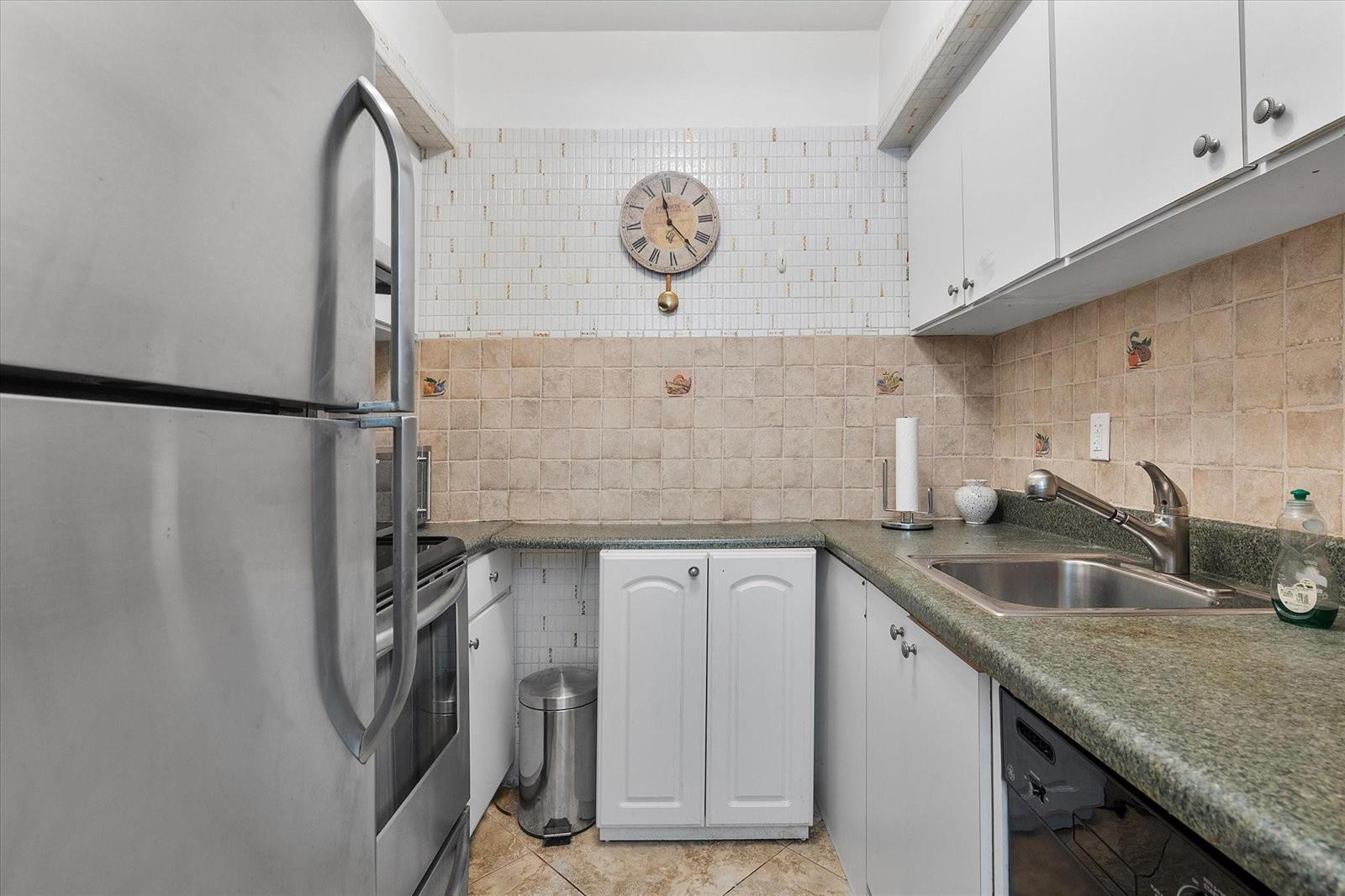 A small galley kitchen features white cabinets, green countertops, stainless steel appliances, and tiled walls — 500 Layne Boulevard # 18, Hallandale Beach FL 33009, HALLANDALE BEACH, FL