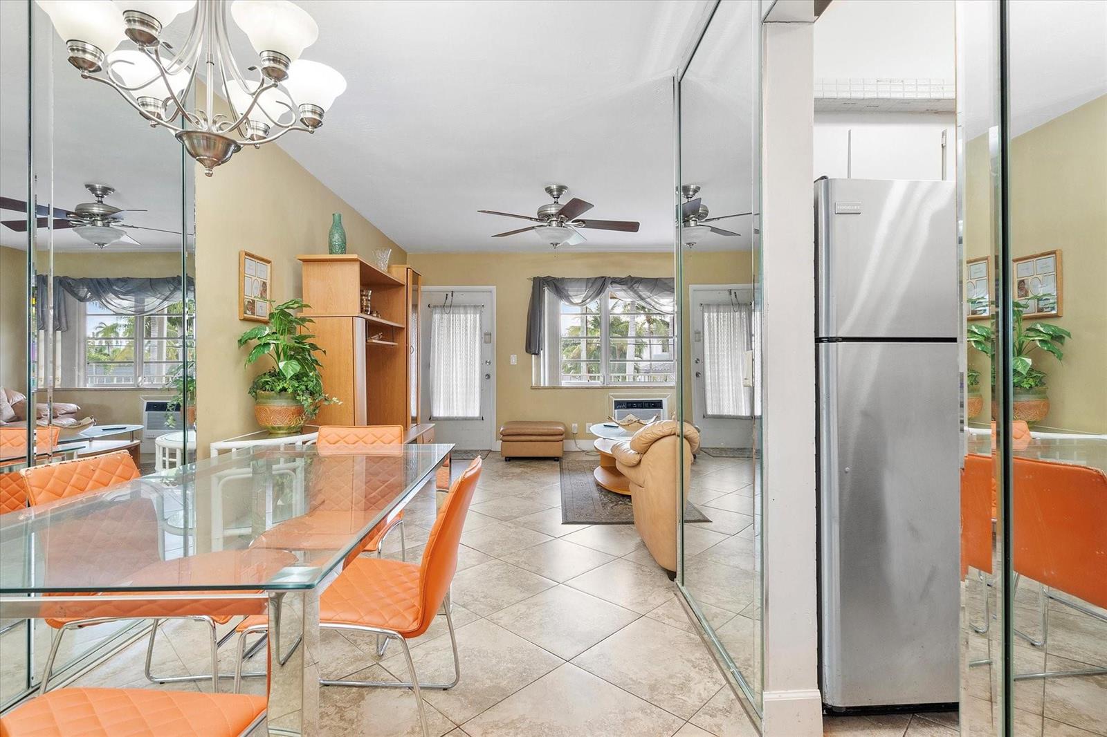 A dining and living area features a glass table, orange chairs, and mirrored wall panels — 500 Layne Boulevard # 18, Hallandale Beach FL 33009, HALLANDALE BEACH, FL