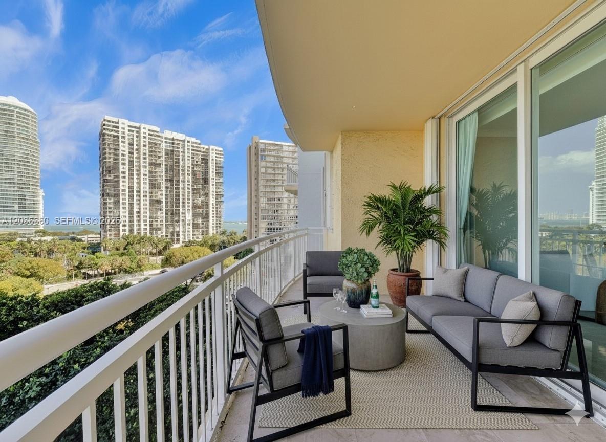 A balcony with outdoor furniture overlooks a city skyline and a body of water — 2475 Brickell Ave # 804, Miami FL 33129, MIAMI, FL