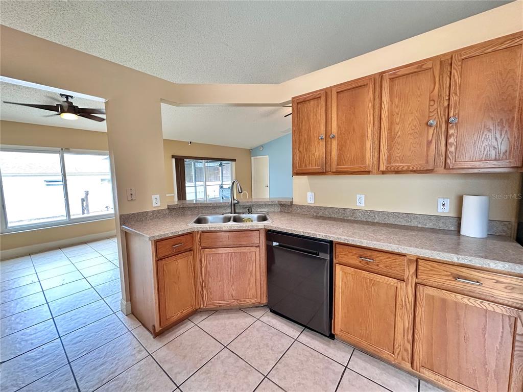 A kitchen features oak cabinets, laminate countertops, a double sink, and a black dishwasher — 1650 NAVIGATOR LANE, TARPON SPRINGS, FL