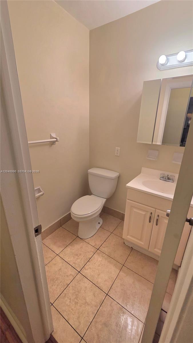 A small bathroom features a white vanity, a toilet, and a tri-fold medicine cabinet — 201 SE 6th Ave # 11, Pompano Beach FL 33060, POMPANO BEACH, FL