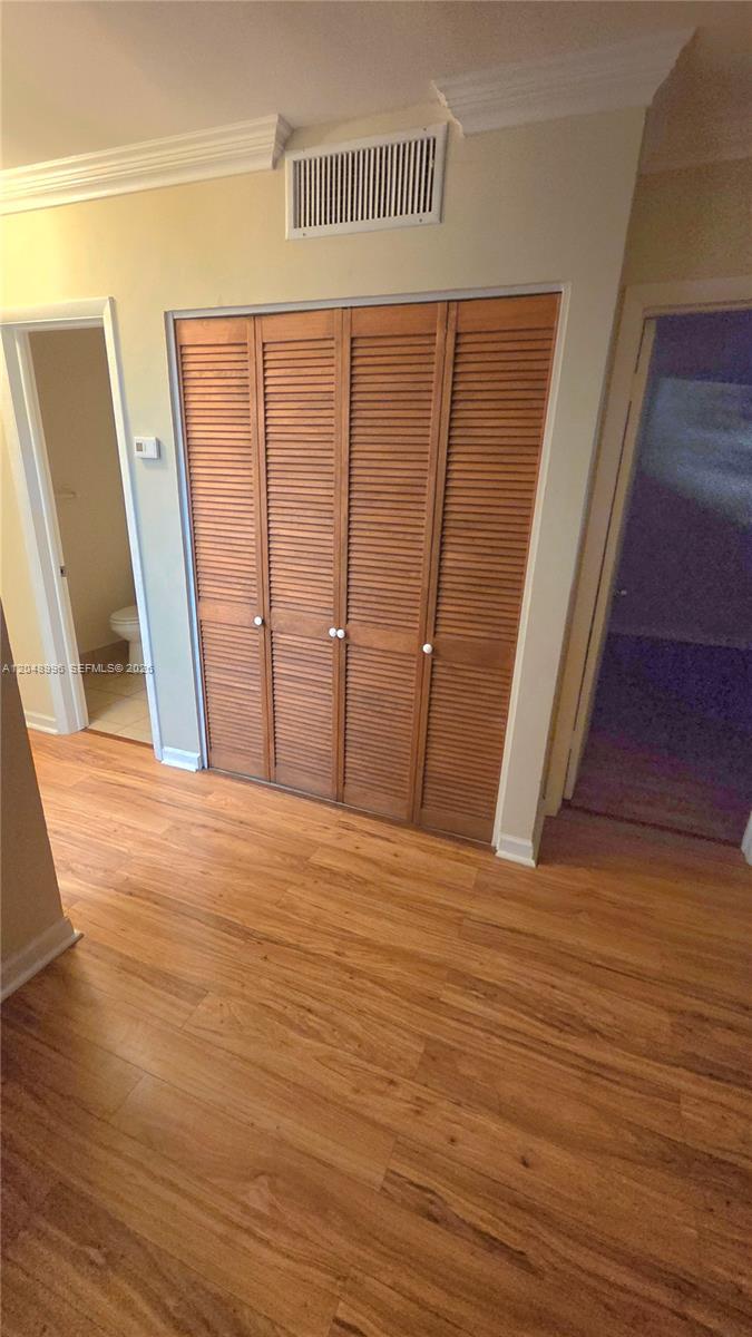 This empty living room features light-colored walls, wood-look flooring, and a kitchen pass-through window — 201 SE 6th Ave # 11, Pompano Beach FL 33060, POMPANO BEACH, FL
