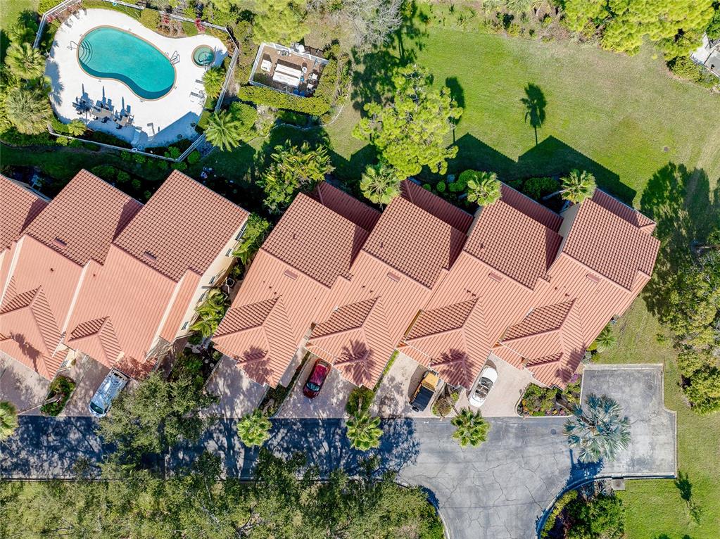 An aerial view shows a row of townhouses with tiled roofs, driveways, and a pool — 3975 SQUARE EAST LANE UNIT 9, SARASOTA, FL