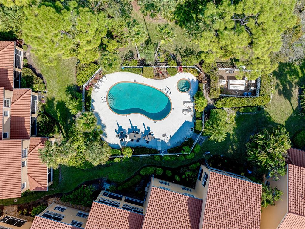 An aerial view shows a community swimming pool and hot tub surrounded by residential buildings — 3975 SQUARE EAST LANE UNIT 9, SARASOTA, FL