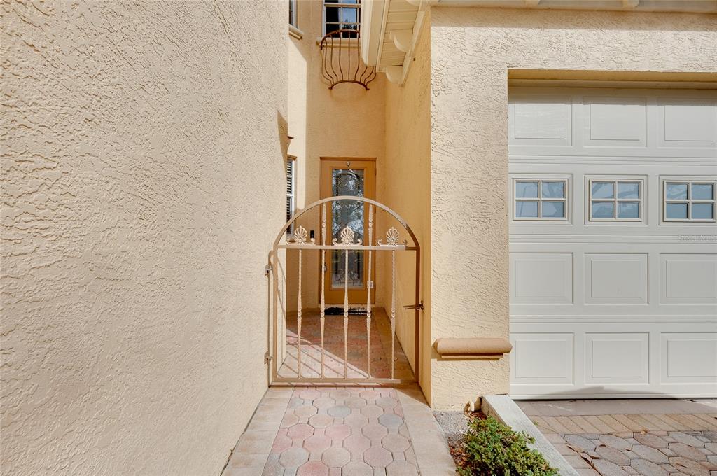 A gated entryway leads to a front door beside a white garage door — 3975 SQUARE EAST LANE UNIT 9, SARASOTA, FL