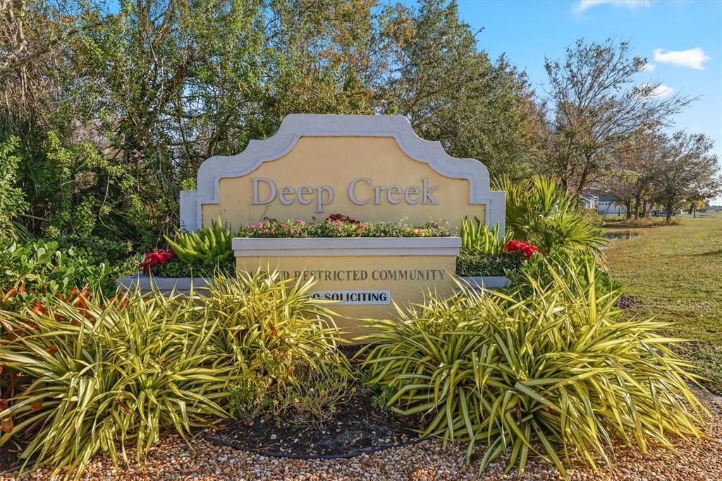A sign for the Deep Creek community stands surrounded by landscaping and trees — 25106 BOLIVAR DRIVE, PUNTA GORDA, FL