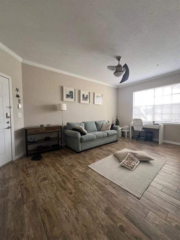 A living room features a blue sofa, a desk, wood-look tile floors, and a ceiling fan — 2632 ROBERT TRENT JONES DRIVE UNIT 134, ORLANDO, FL