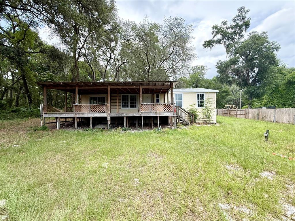 A yellow mobile home with a large wooden deck sits on a grassy lot — 5756 NE 165TH TERRACE ROAD, SILVER SPRINGS, FL