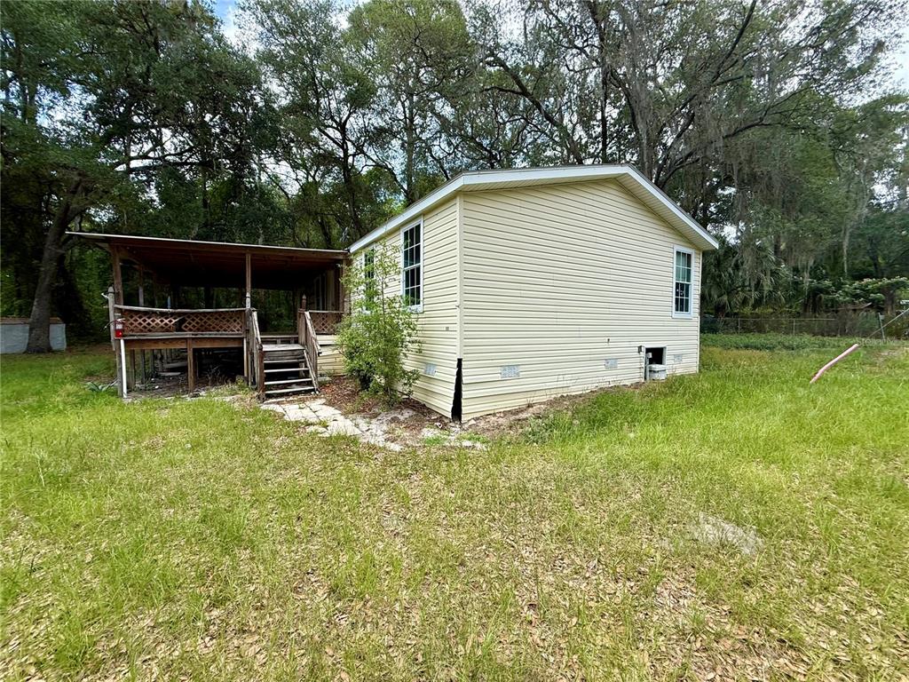 A yellow mobile home with a wooden deck and porch sits in a grassy yard — 5756 NE 165TH TERRACE ROAD, SILVER SPRINGS, FL