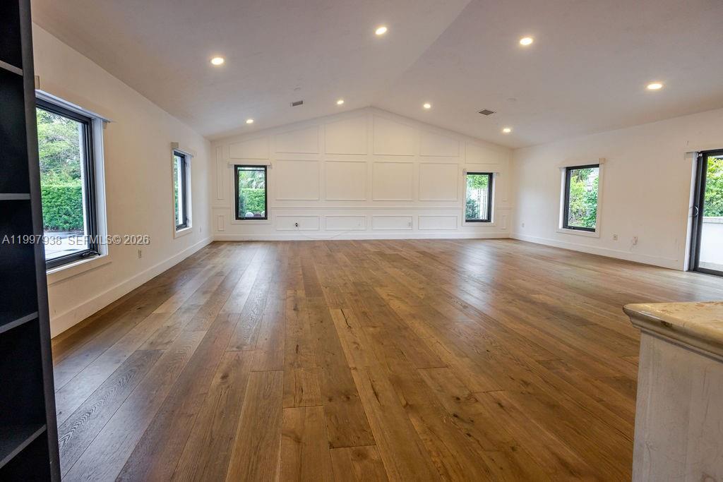 A spacious, empty room features light wood floors, white walls with wainscoting, and recessed lighting — 11301 SW 95th St, Miami FL 33176, MIAMI, FL