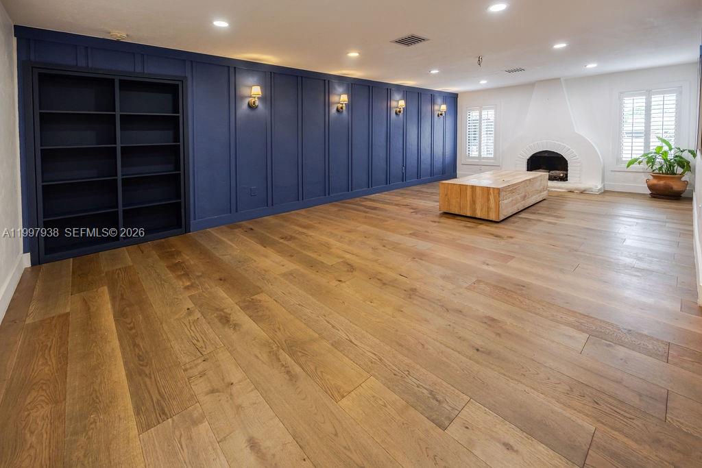 A spacious room features light wood floors, a blue paneled wall with shelving, and a fireplace — 11301 SW 95th St, Miami FL 33176, MIAMI, FL