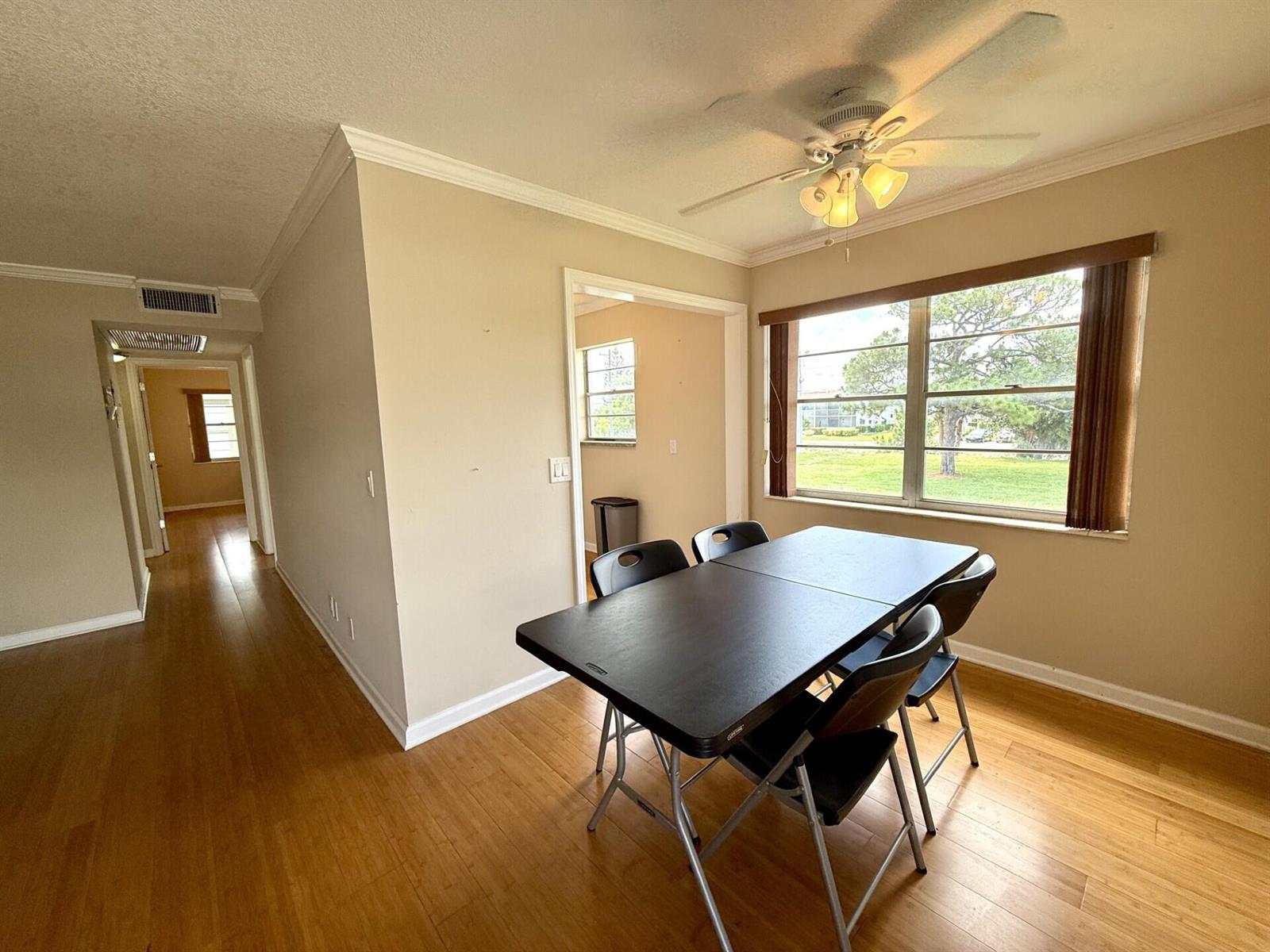A dining area features a black folding table, four chairs, hardwood floors, and a window — 73 Hastings E, West Palm Beach FL 33417, WEST PALM BEACH, FL