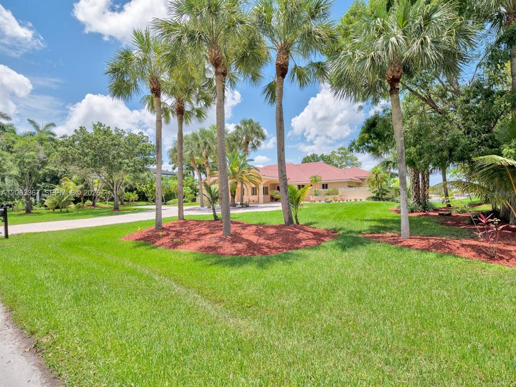A single-story house with a red tile roof sits behind a landscaped lawn and palm trees — 2710 WALKERS WAY, WESTON, FL