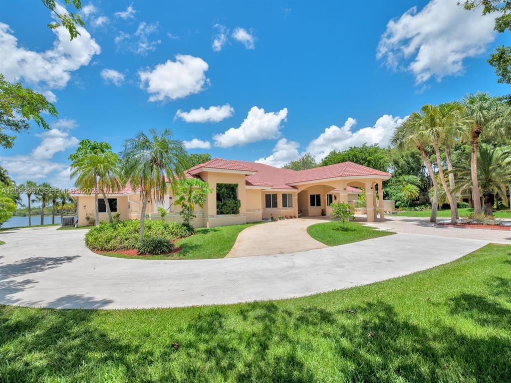 A single-story house with a beige exterior, a red tile roof, and a curved driveway — 2710 WALKERS WAY, WESTON, FL
