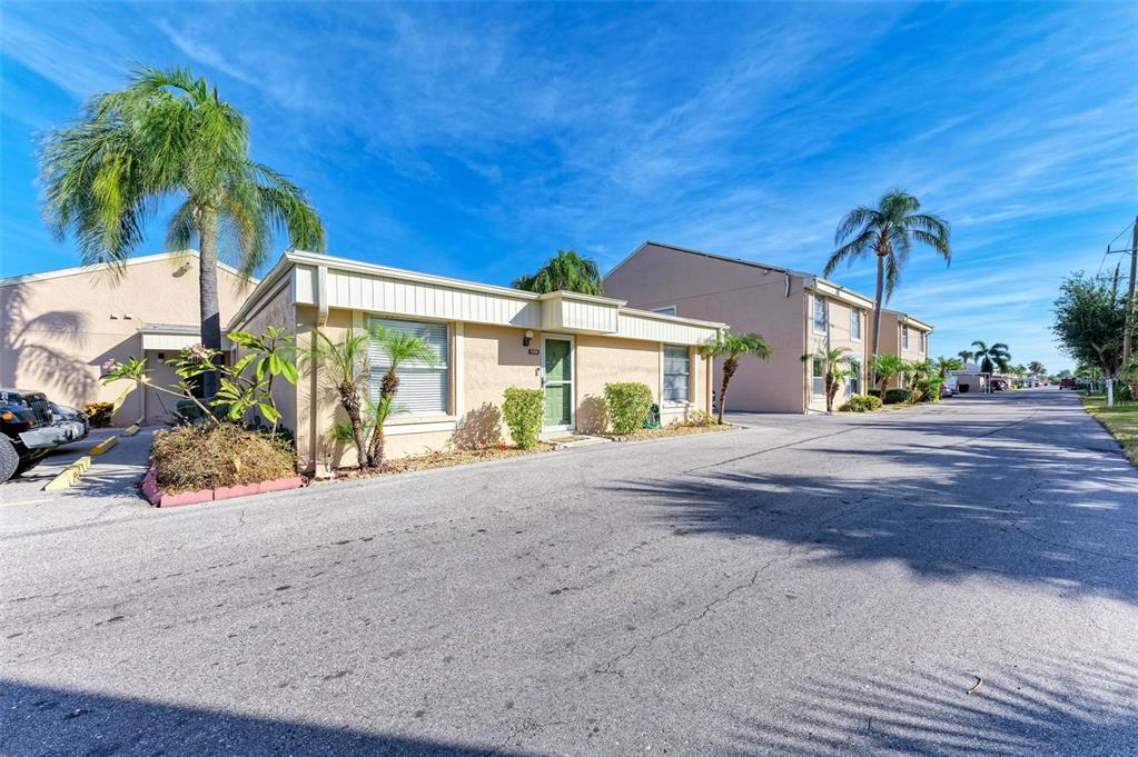 A single-story tan stucco building with a green door and palm trees in front — 6336 7TH AVENUE W UNIT 6336, BRADENTON, FL