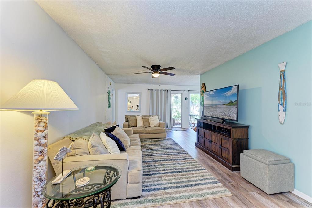 A living room features a beige sofa, a striped rug, and a television on a console — 6336 7TH AVENUE W UNIT 6336, BRADENTON, FL