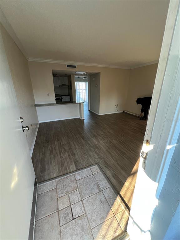 An entryway with tiled flooring leads into a living room with wood-look flooring and kitchen — 136 BLUE POINT WAY UNIT 310, ALTAMONTE SPRINGS, FL