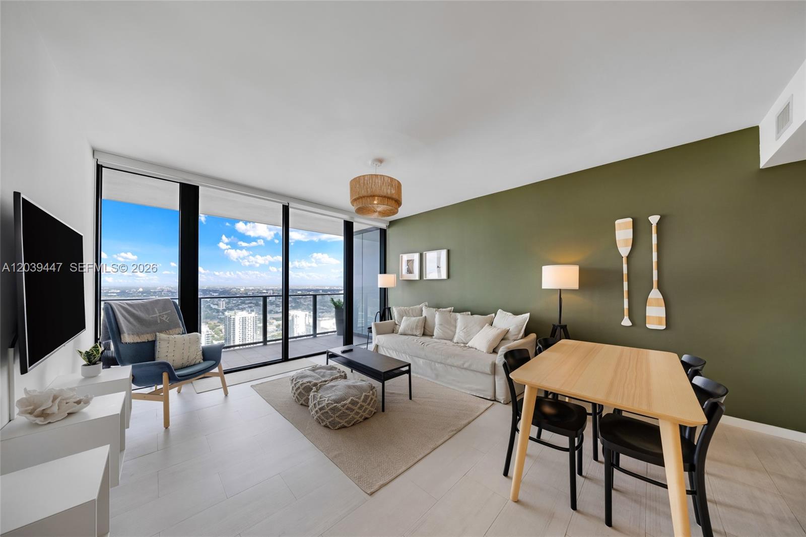 A modern living and dining area features an olive green wall, floor-to-ceiling windows, and furniture — 1000 Brickell Plz # 4704, Miami FL 33131, MIAMI, FL