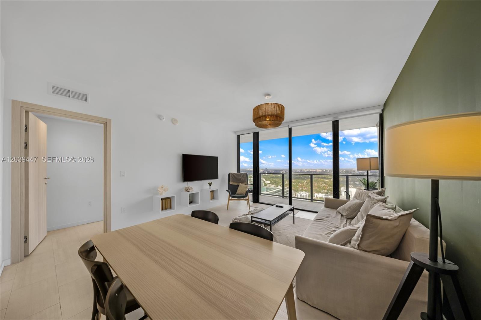 A modern living and dining area features a beige sofa, wood table, and floor-to-ceiling windows — 1000 Brickell Plz # 4704, Miami FL 33131, MIAMI, FL
