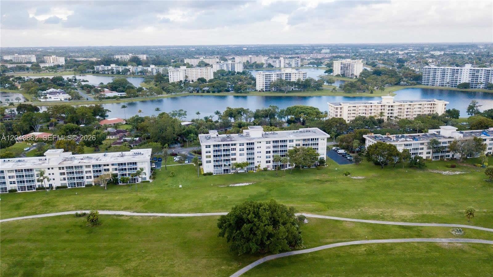 An aerial view shows several multi-story apartment buildings situated around a large lake and golf course — 3200 N Palm Aire Dr # 305, Pompano Beach FL 33069, POMPANO BEACH, FL