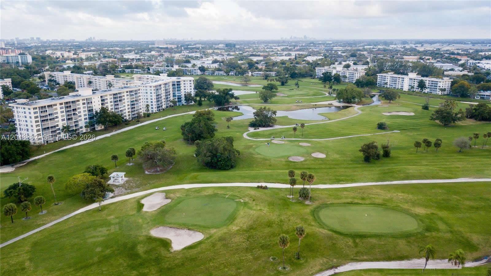An aerial view shows a golf course with multiple greens, ponds, and surrounding apartment buildings — 3200 N Palm Aire Dr # 305, Pompano Beach FL 33069, POMPANO BEACH, FL