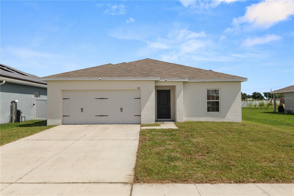 A single-story house with a white stucco exterior, a two-car garage, and a brown roof — 913 EAGLE ROCK TERRACE, WINTER HAVEN, FL