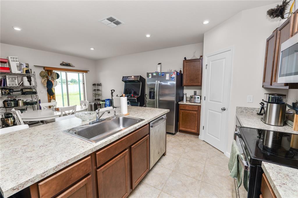 A kitchen features a large island with a sink, stainless steel appliances, and wood cabinets — 913 EAGLE ROCK TERRACE, WINTER HAVEN, FL