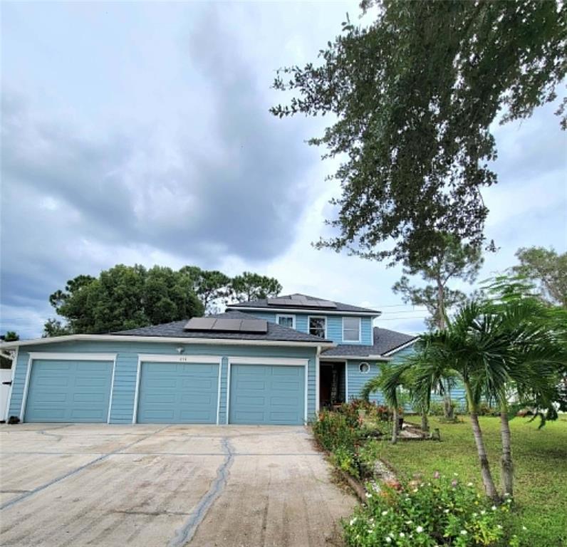 A blue two-story house features a three-car garage, solar panels, and a concrete driveway — 654 MADRID DRIVE, KISSIMMEE, FL