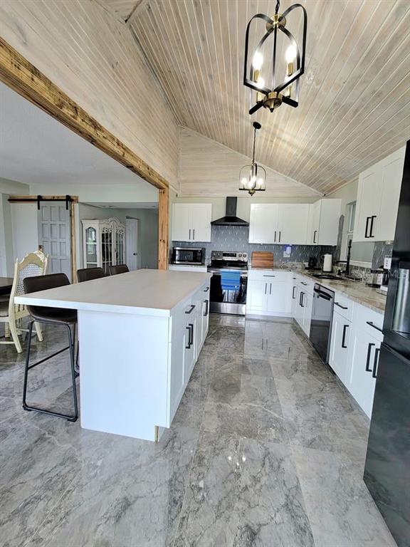 A modern kitchen features white cabinetry, a large island, and gray marble-look tile flooring — 654 MADRID DRIVE, KISSIMMEE, FL