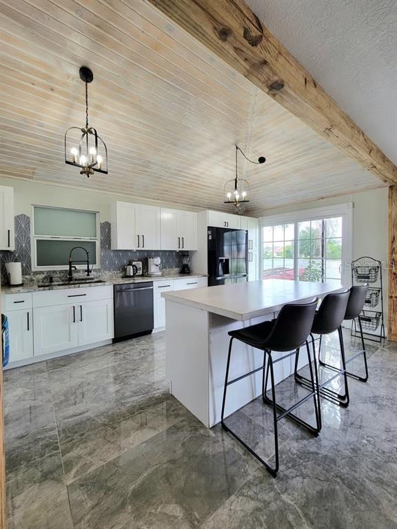 A kitchen features white cabinets, a central island with bar stools, and a wood-paneled ceiling — 654 MADRID DRIVE, KISSIMMEE, FL