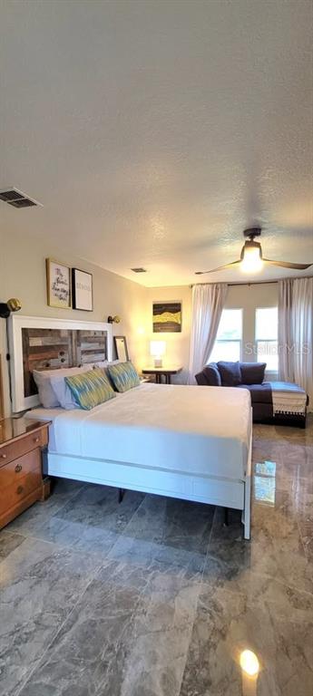 A bedroom features a bed with a rustic headboard, tile flooring, and a ceiling fan — 654 MADRID DRIVE, KISSIMMEE, FL