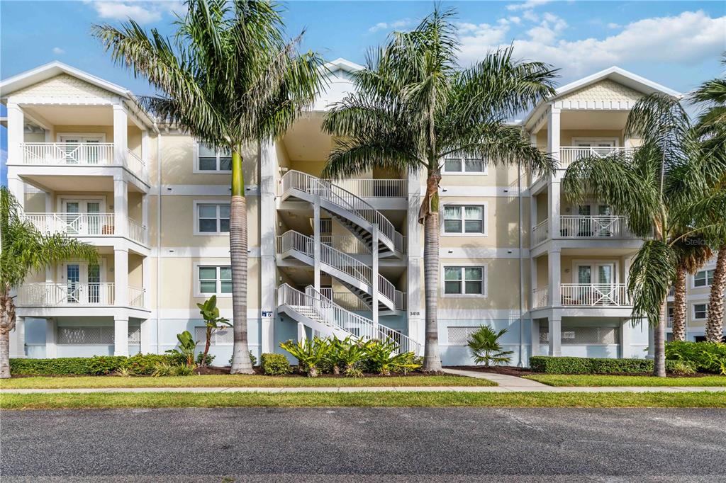 A three-story apartment building with exterior staircases, balconies, and palm trees in front — 3418 79TH STREET CIRCLE W UNIT 101, BRADENTON, FL