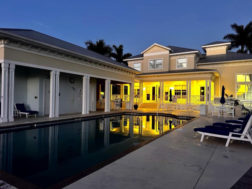 A swimming pool sits in front of a two-story building with a covered patio at dusk — 3418 79TH STREET CIRCLE W UNIT 101, BRADENTON, FL