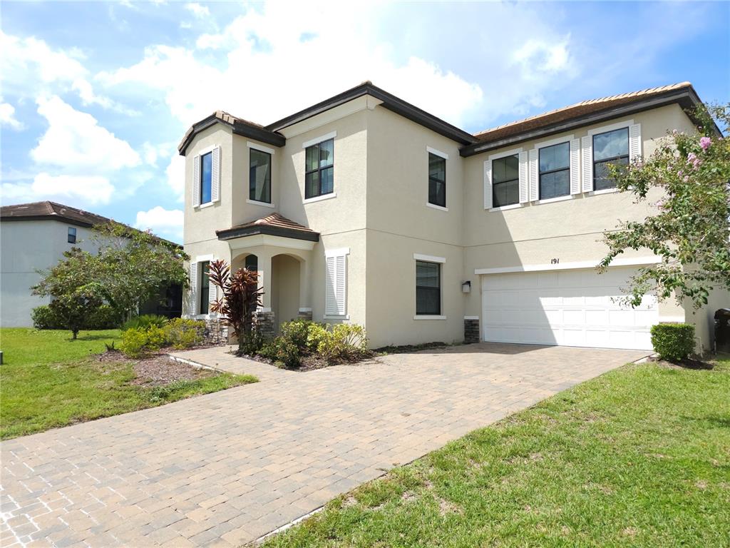 A two-story beige house with a paved driveway and a white two-car garage — 191 AIDANS LANDING, HAINES CITY, FL